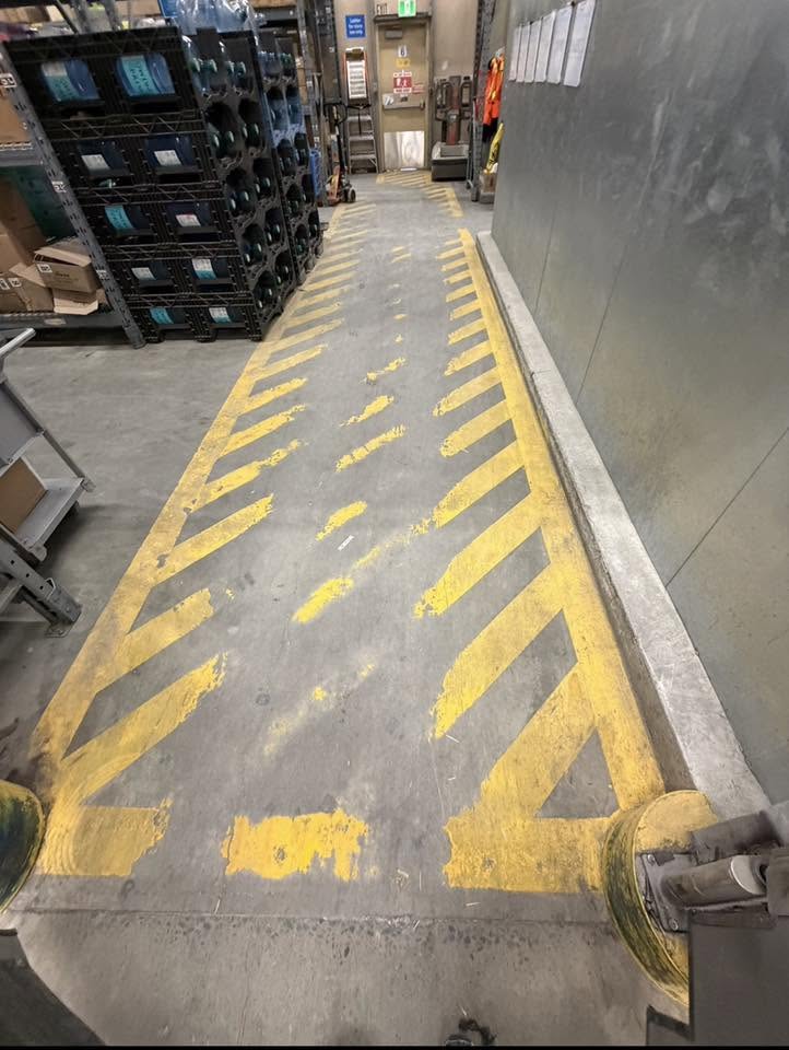 Warehouse floor with worn, faded safety markings