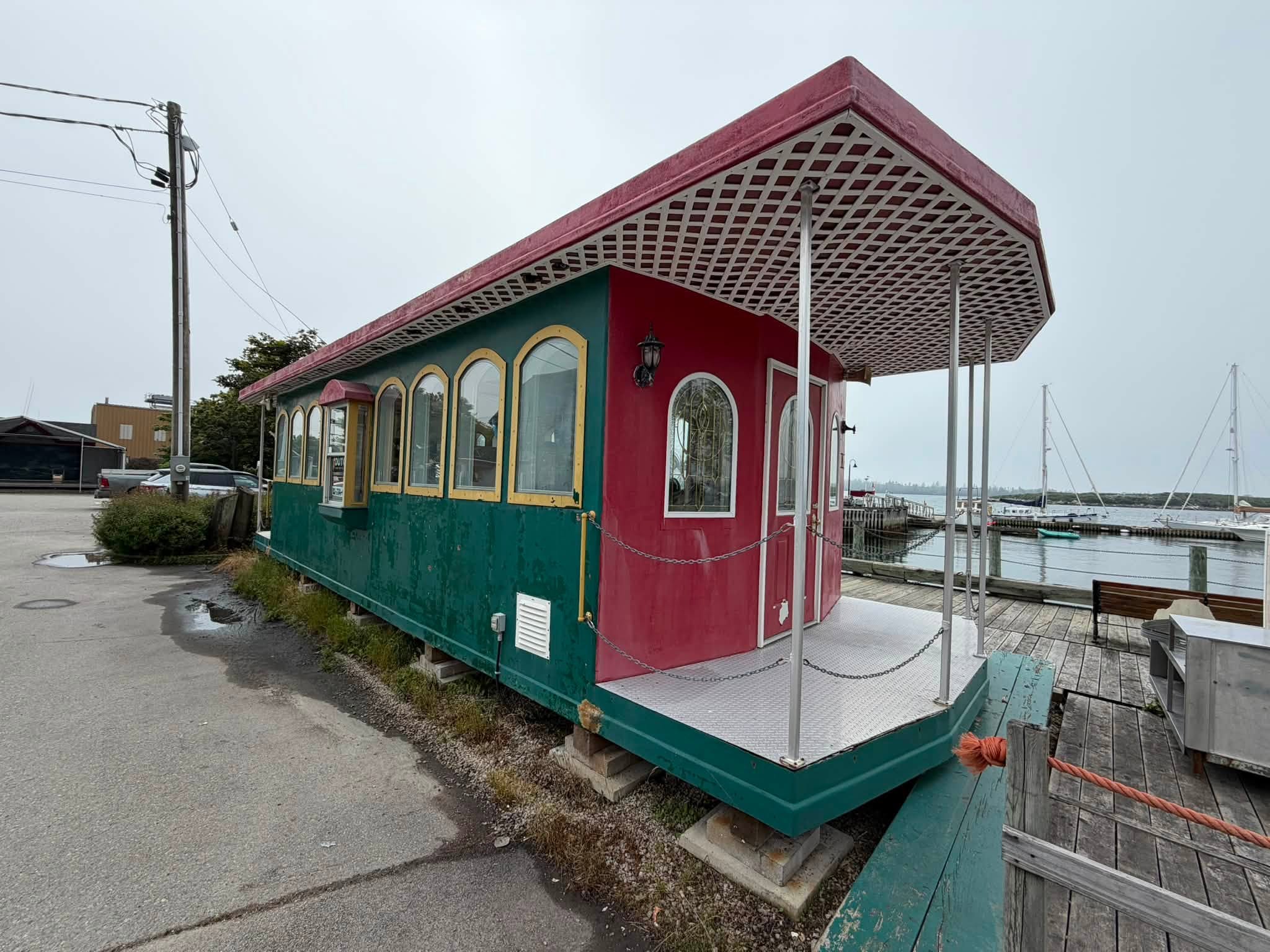 Railcar-style waterfront building with faded, peeling green and red paint before repainting