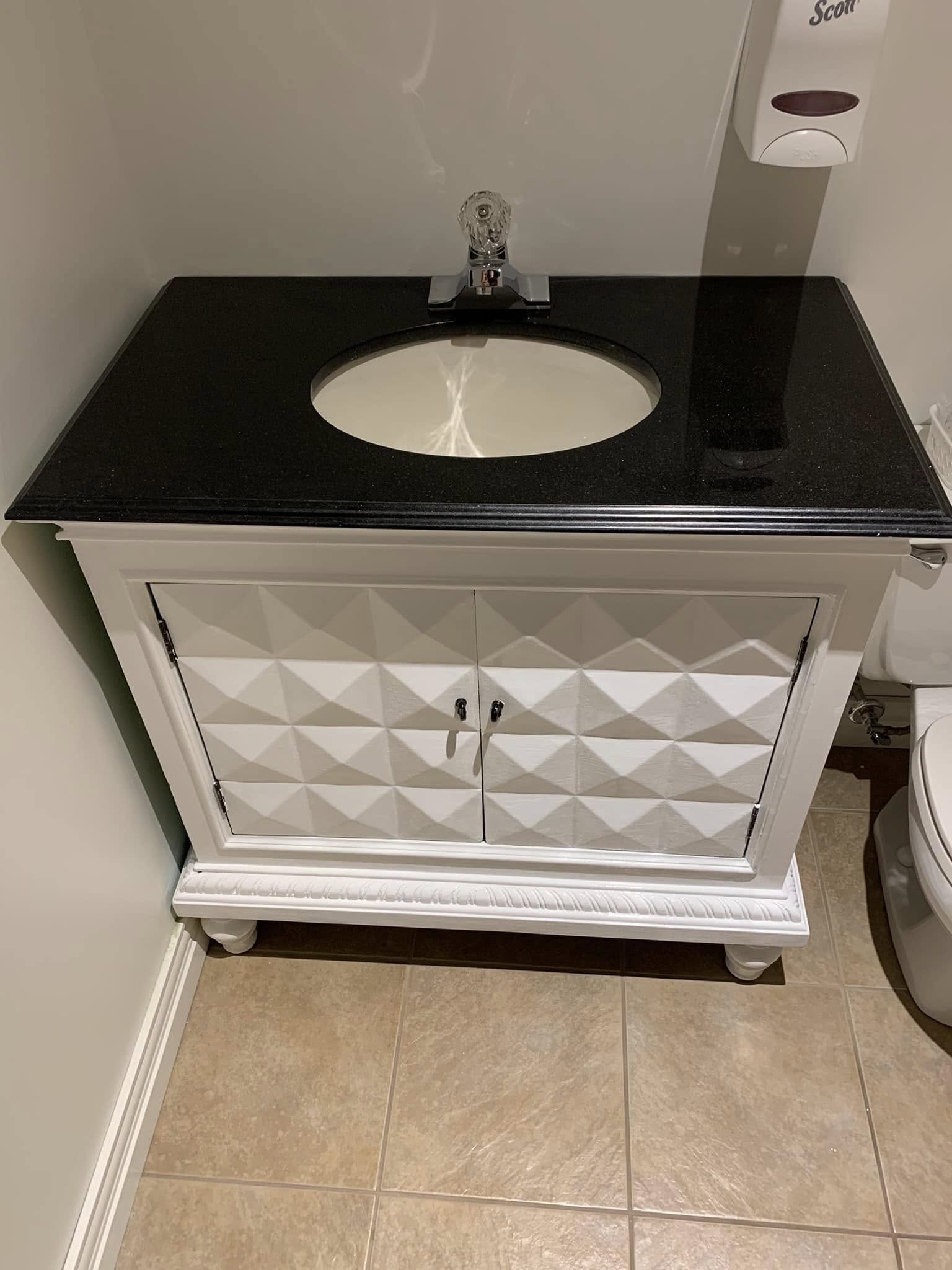 Bathroom vanity refinished in clean modern white with black granite top
