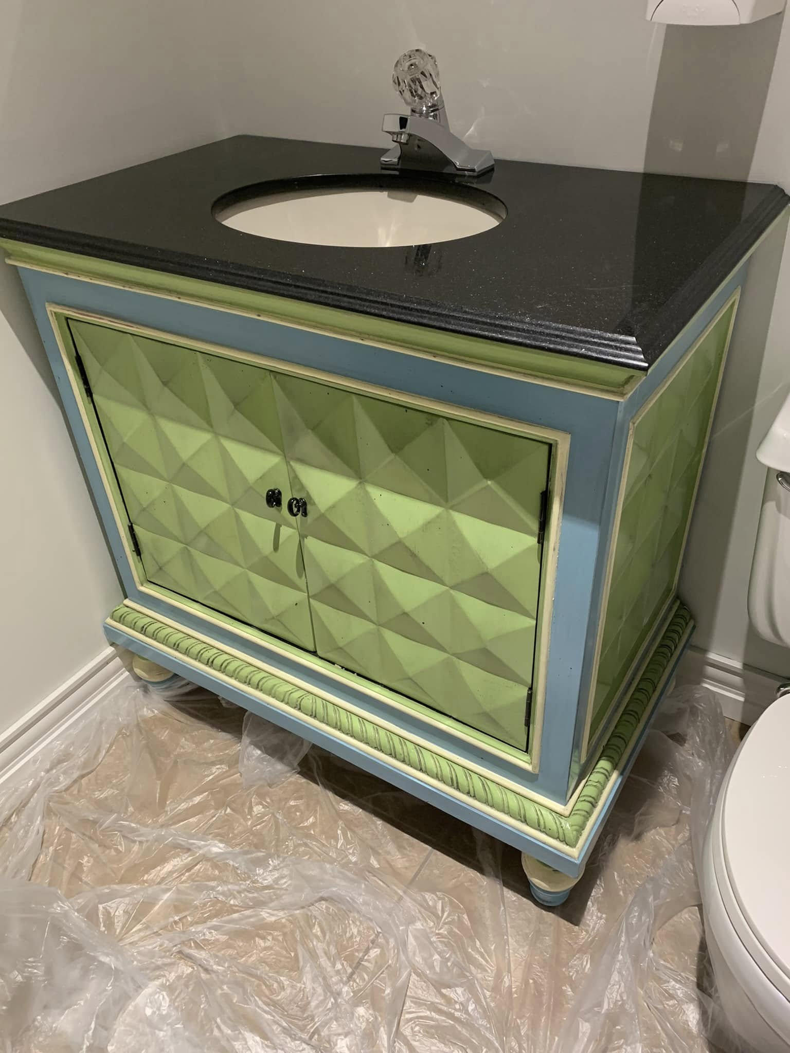 Dated green and blue bathroom vanity with textured front before refinishing