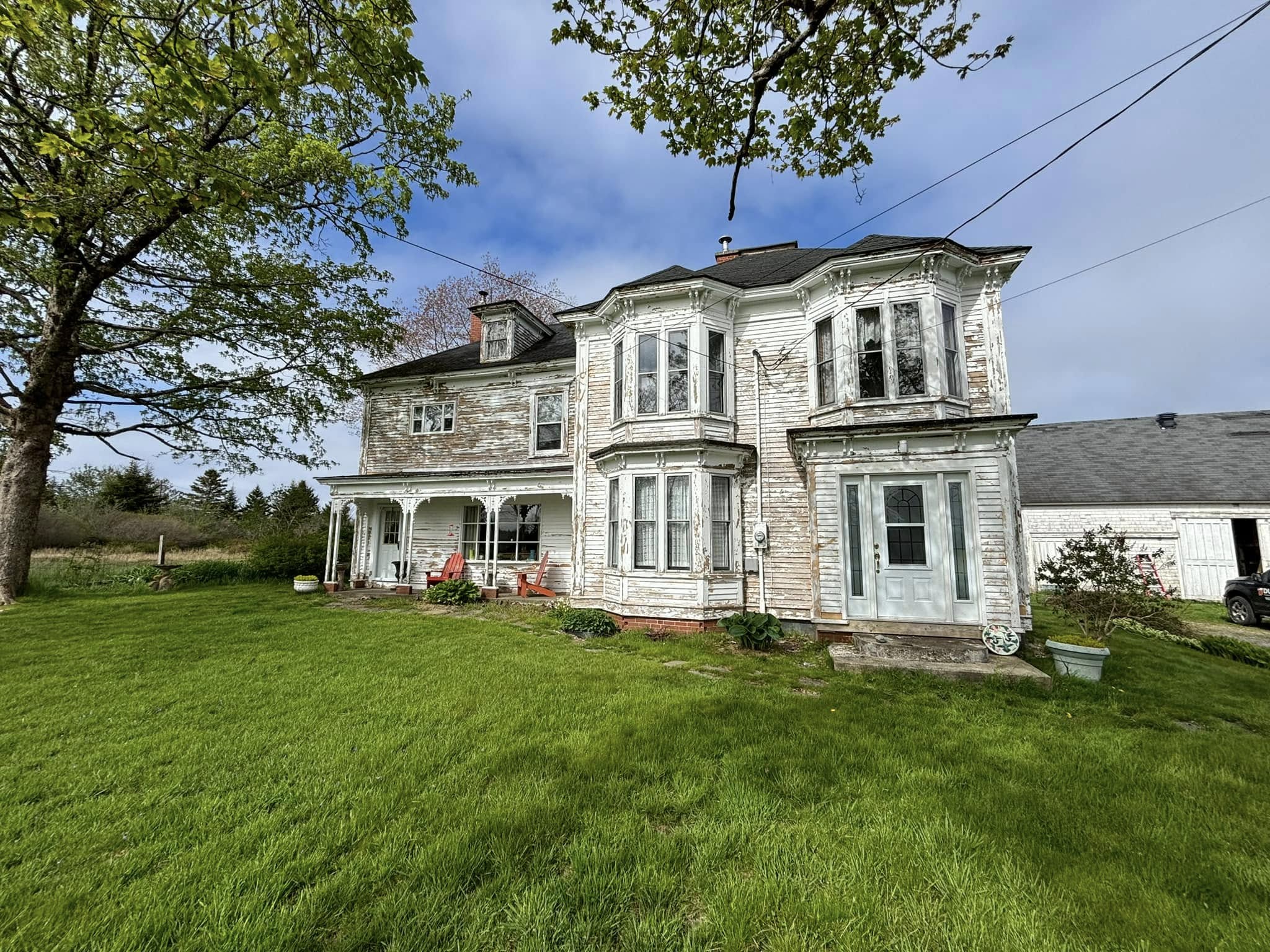 Two-storey farmhouse with heavily weathered, peeling clapboard before painting