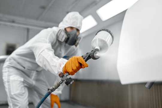 Painter in protective coveralls and respirator spray-finishing a panel in the Dutch Painting Services spray booth