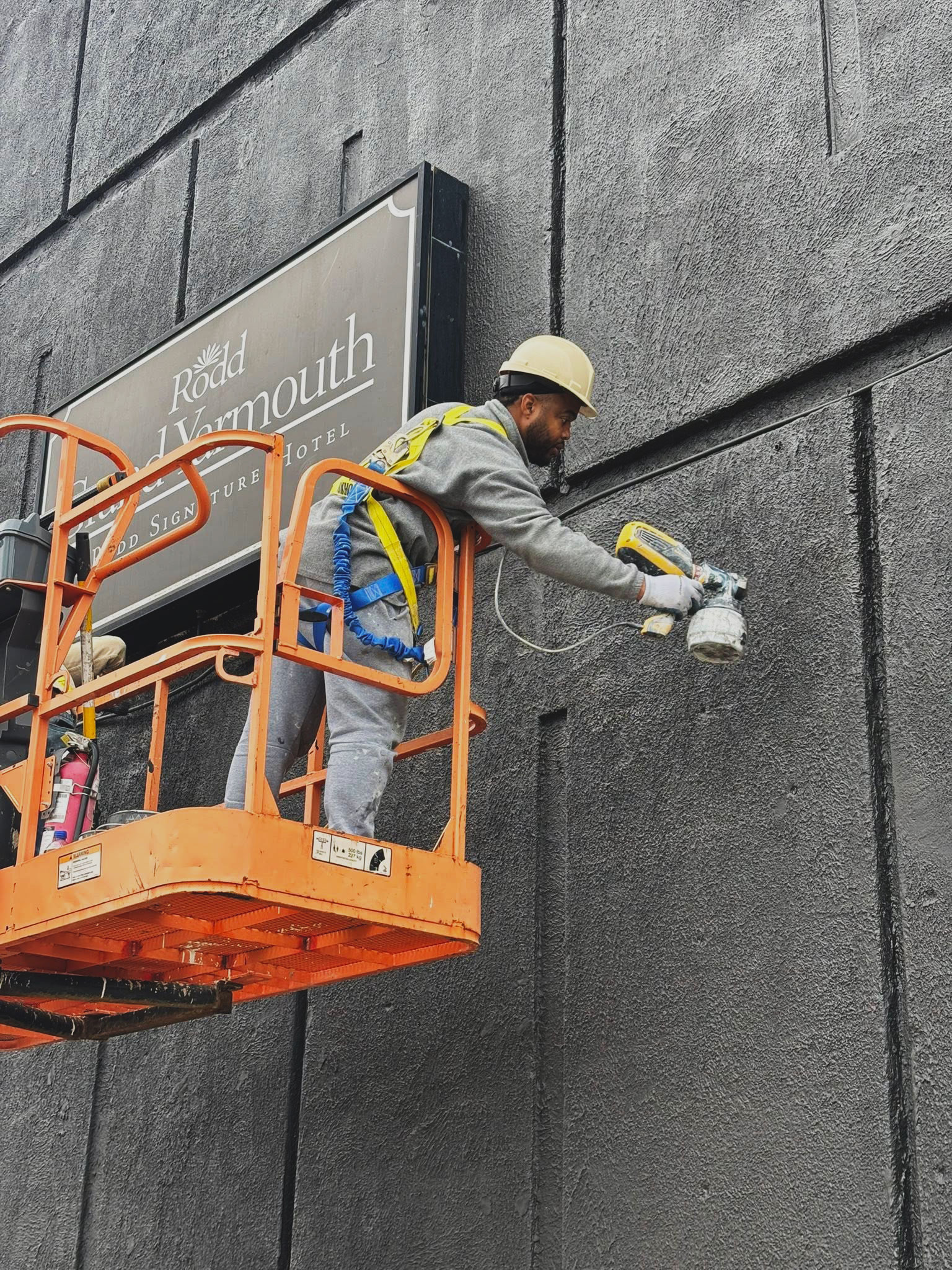 Dutch Painting Services technician spray-painting a commercial building exterior in Yarmouth, Nova Scotia